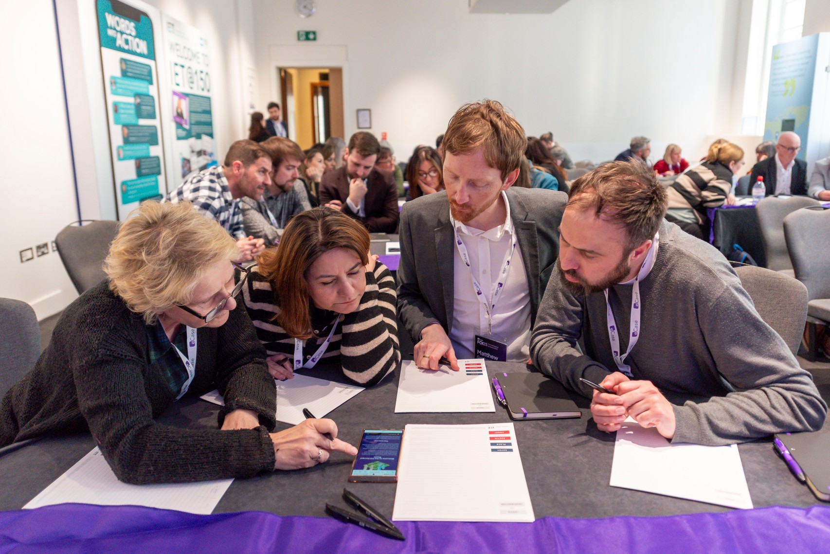 A group of people at a table looking at an escape room challenge on a mobile phone